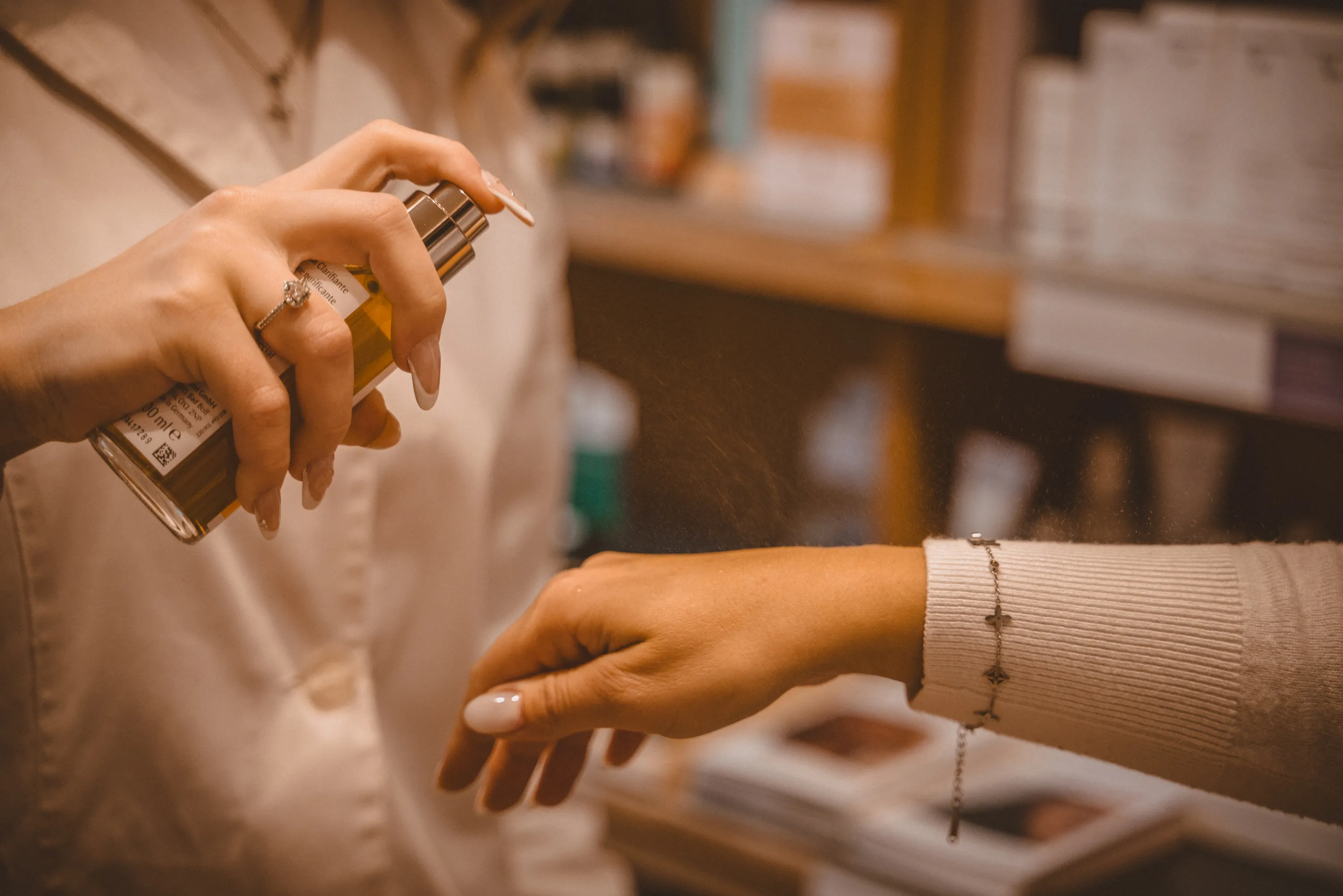 Mitarbeiterin sprüht Dr. Hauschka-Spray auf Handgelenk der Kundin, Nahaufnahme
